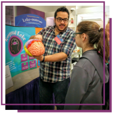 A NINDS employee showing a model of a brain to middle school students